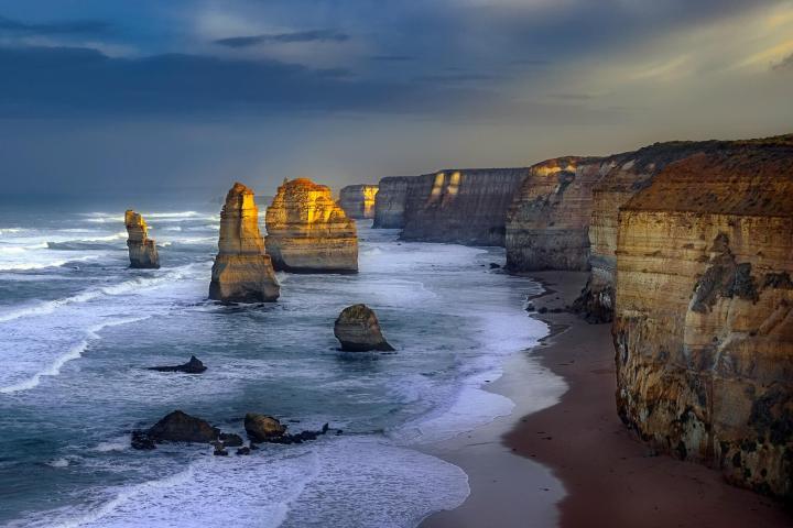 water next to the rock with The Twelve Apostles in the background